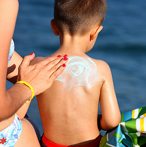  Adult applying sunscreen to the back of a young child