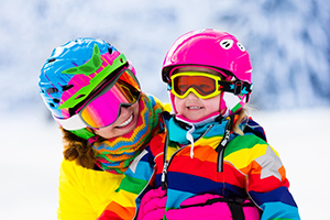 Adult and child dressed for winter activity, wearing helmets