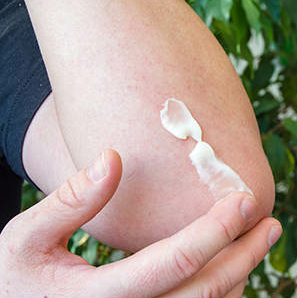 applying ointment to an elbow with a light rash
